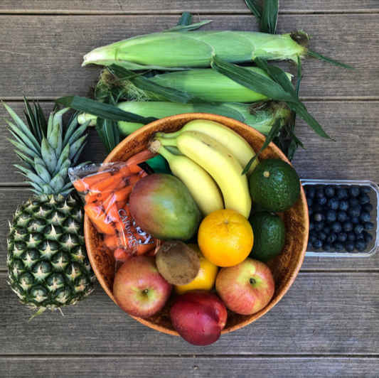 Large bowl of fruit and vegetables on a wooden background.