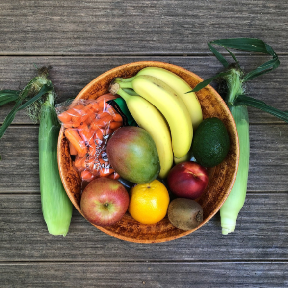 Small bowl of fruit and vegetables on a wooden background.